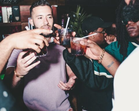 three people holding glass bottles while talking