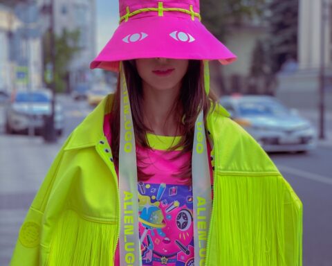 woman in green jacket wearing pink hat