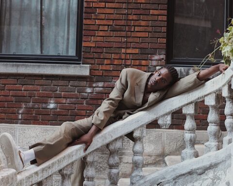 man in brown jacket lying on white bench during daytime